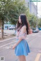 A woman in a blue skirt is standing on the street.