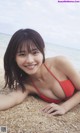 A woman in a red bikini laying on the beach.