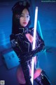 A woman in a latex outfit holding a light saber.