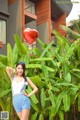 A woman holding a red heart shaped balloon in front of a building.