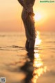 A woman standing in the water at sunset. 