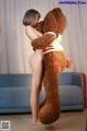 A woman is hugging a large teddy bear on the floor.