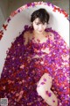 A woman sitting in a bathtub filled with rose petals.