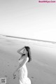 A woman in a white dress standing on a beach.