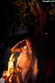 A naked woman standing in front of a fire.