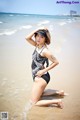 A woman in a black and white bathing suit on the beach.