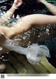 A woman in a white dress floating in a pool of water.