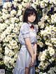 A woman standing in front of a bunch of white flowers.