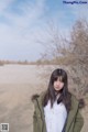 A woman standing in the middle of a dirt road.